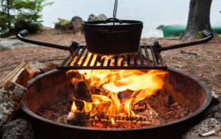 Someone cooking one of their recipes in a Dutch oven over a campfire.