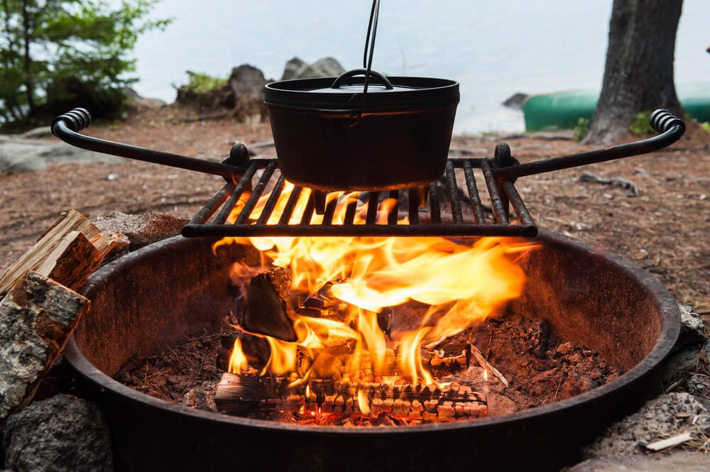 Someone cooking one of their recipes in a Dutch oven over a campfire.