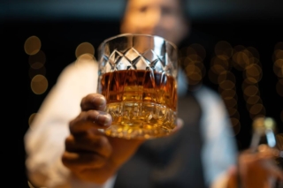 A bartender serving a glass of bourbon at the Hochatown distillery.